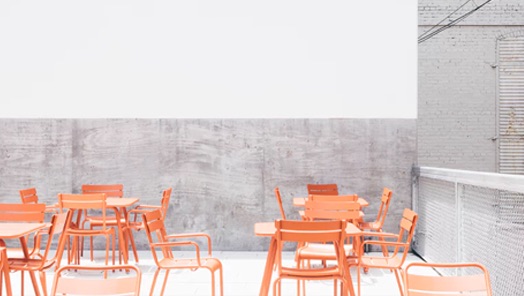 a space full of orange chairs and tables